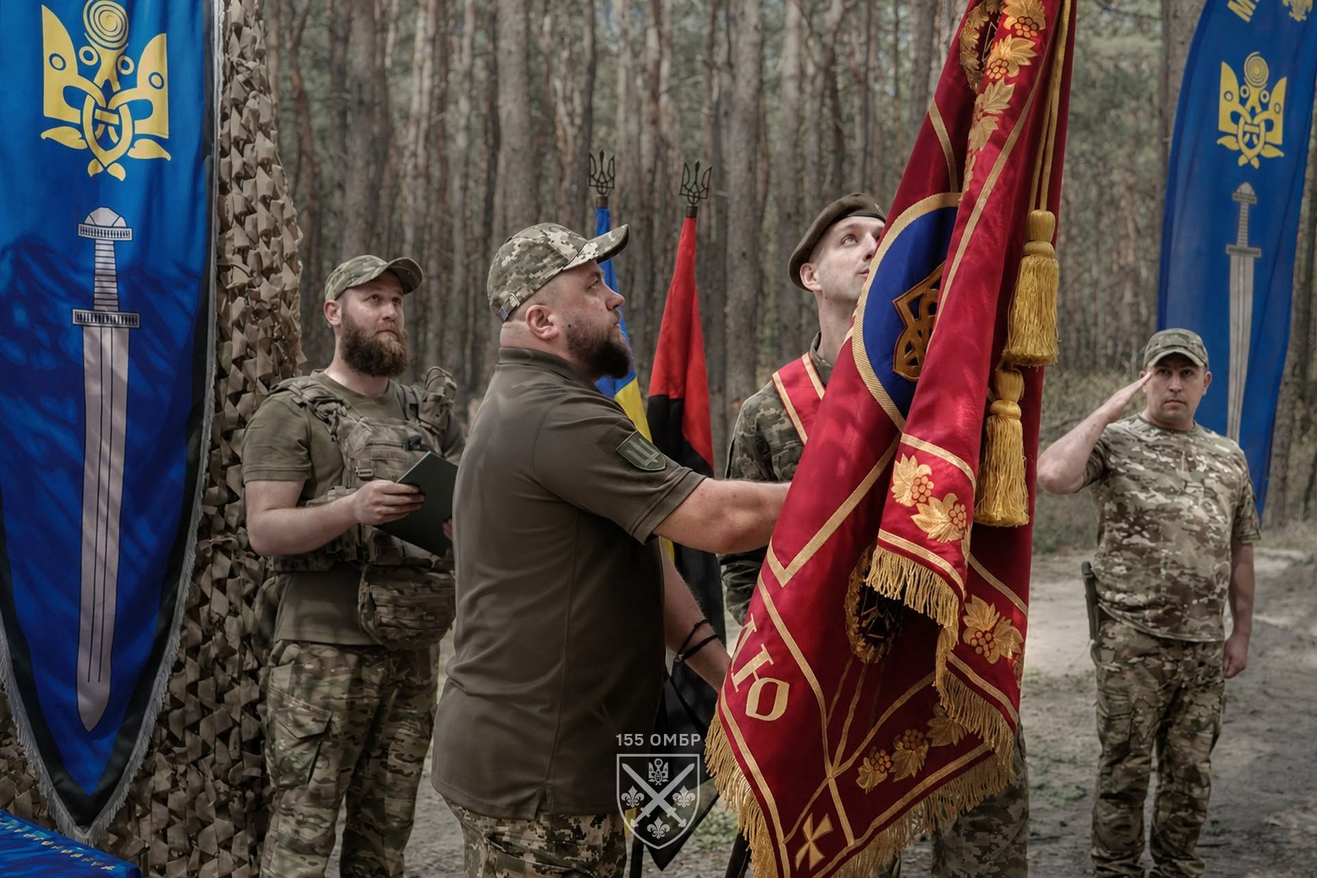 Полковник Андрій Крока тримає бойовий прапор 155 окремої механізованої бригади під час церемонії